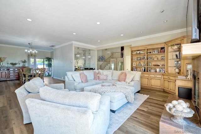 living room with light hardwood / wood-style floors, crown molding, and a chandelier