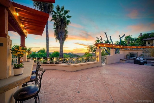 patio terrace at dusk featuring exterior fireplace