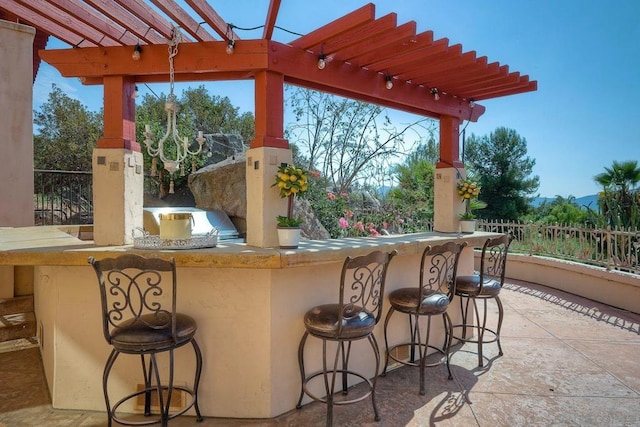 view of patio / terrace featuring exterior kitchen, a bar, and a pergola