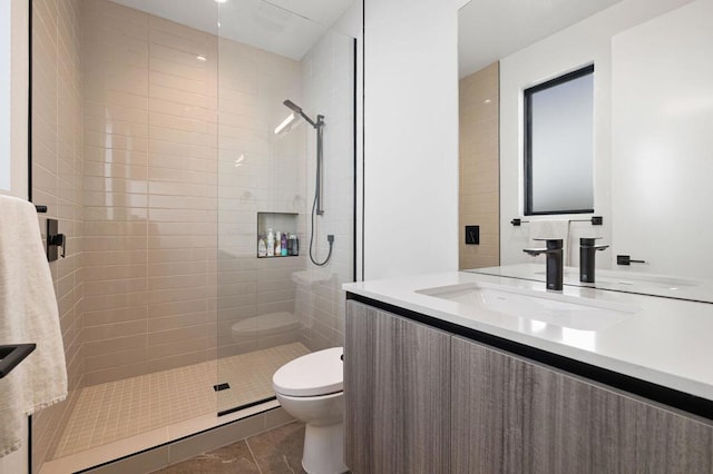 bathroom with toilet, vanity, tile patterned flooring, and a tile shower