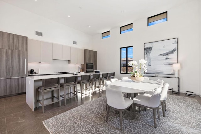 dining area featuring sink and a towering ceiling