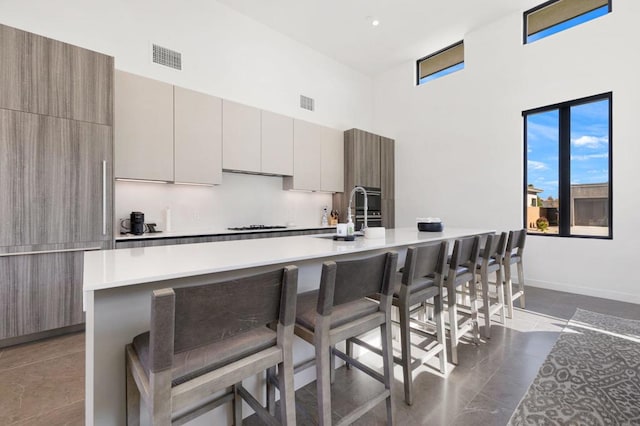 kitchen featuring a high ceiling, sink, a large island with sink, and a breakfast bar