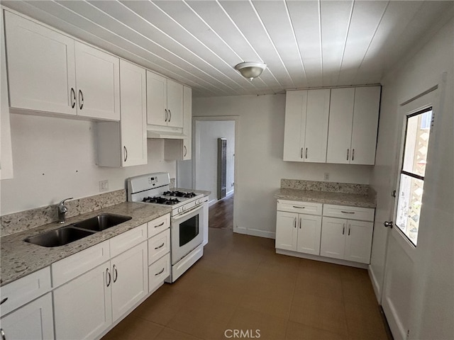 kitchen featuring light stone counters, sink, white cabinets, and white gas stove