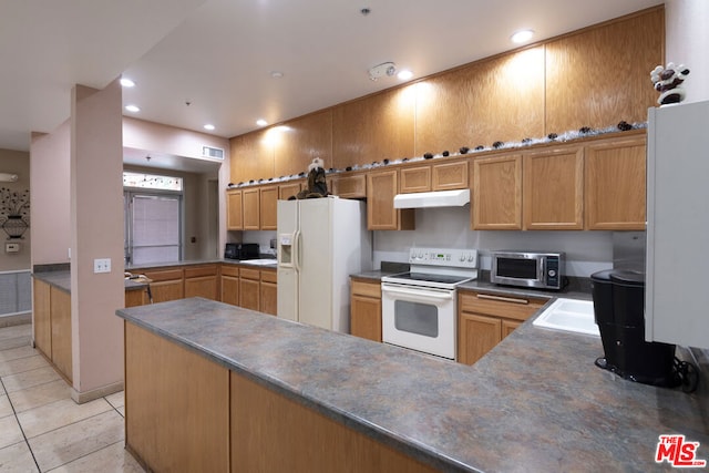 kitchen featuring light tile patterned floors, white appliances, sink, and kitchen peninsula