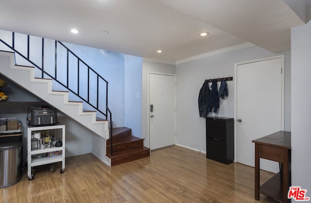 entryway with ornamental molding and hardwood / wood-style floors