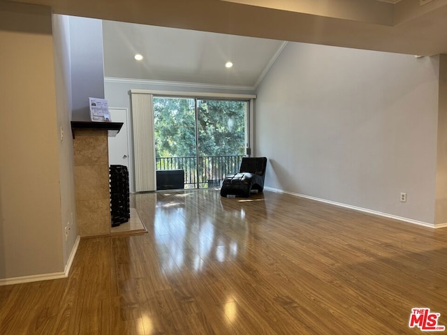 interior space featuring a tiled fireplace, crown molding, and wood-type flooring