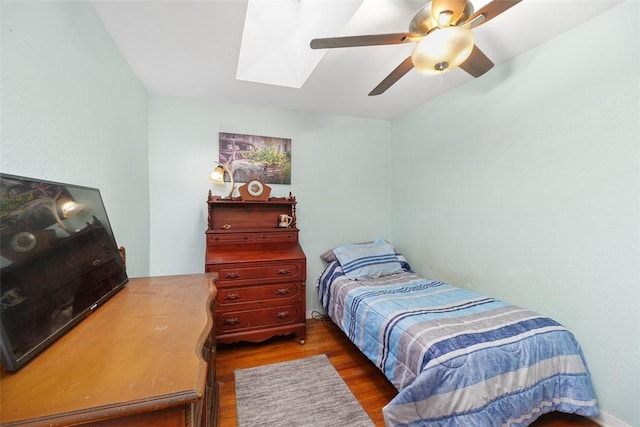 bedroom with ceiling fan, dark wood-type flooring, and a skylight