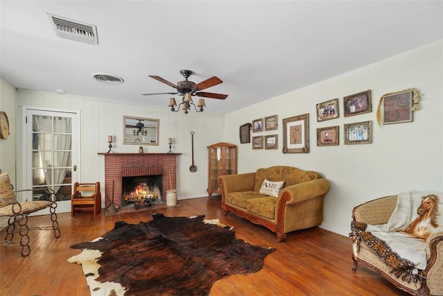 living room featuring a brick fireplace, hardwood / wood-style flooring, and ceiling fan