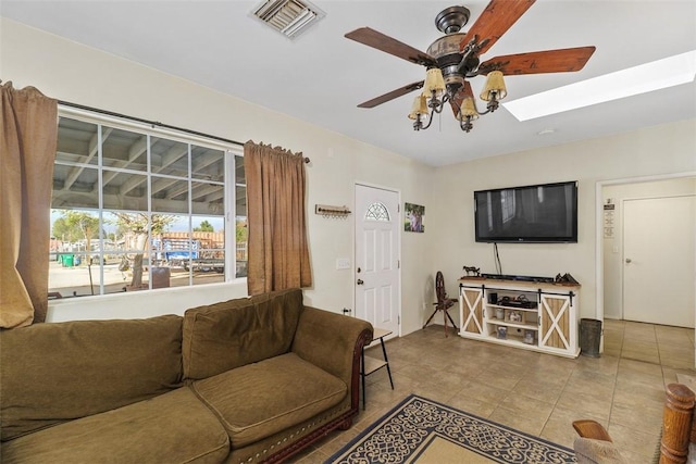 tiled living room with ceiling fan and a skylight