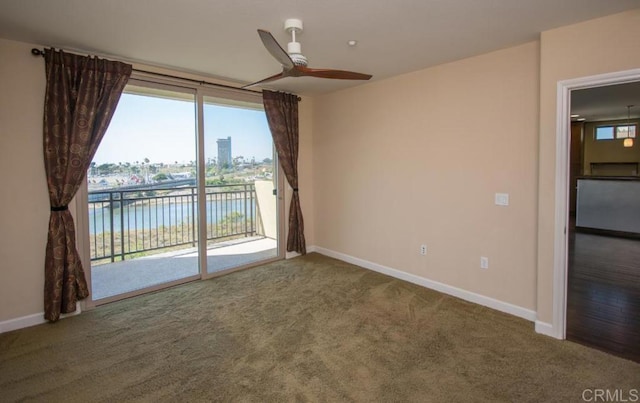 spare room featuring ceiling fan, a wealth of natural light, a water view, and carpet