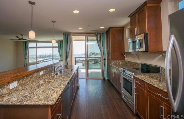 kitchen featuring sink, decorative light fixtures, light stone countertops, dark hardwood / wood-style floors, and appliances with stainless steel finishes