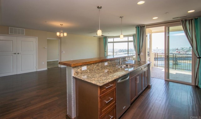 kitchen featuring dishwasher, an inviting chandelier, a kitchen island with sink, and pendant lighting