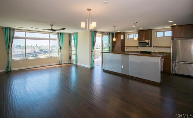 kitchen featuring stainless steel appliances, ceiling fan with notable chandelier, hanging light fixtures, and dark wood-type flooring