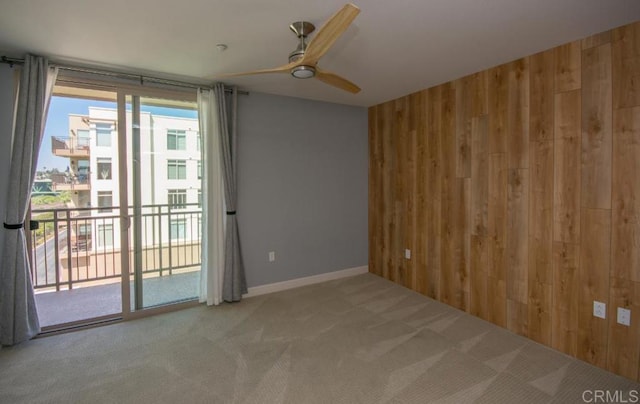 carpeted empty room with wooden walls and ceiling fan