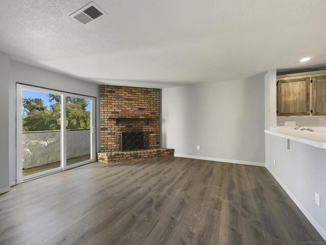 unfurnished living room with a textured ceiling, dark hardwood / wood-style flooring, and a fireplace