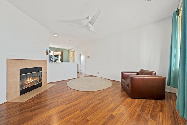 living room with hardwood / wood-style flooring, ceiling fan, and a fireplace