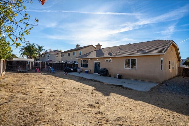 back of property with a patio and a playground