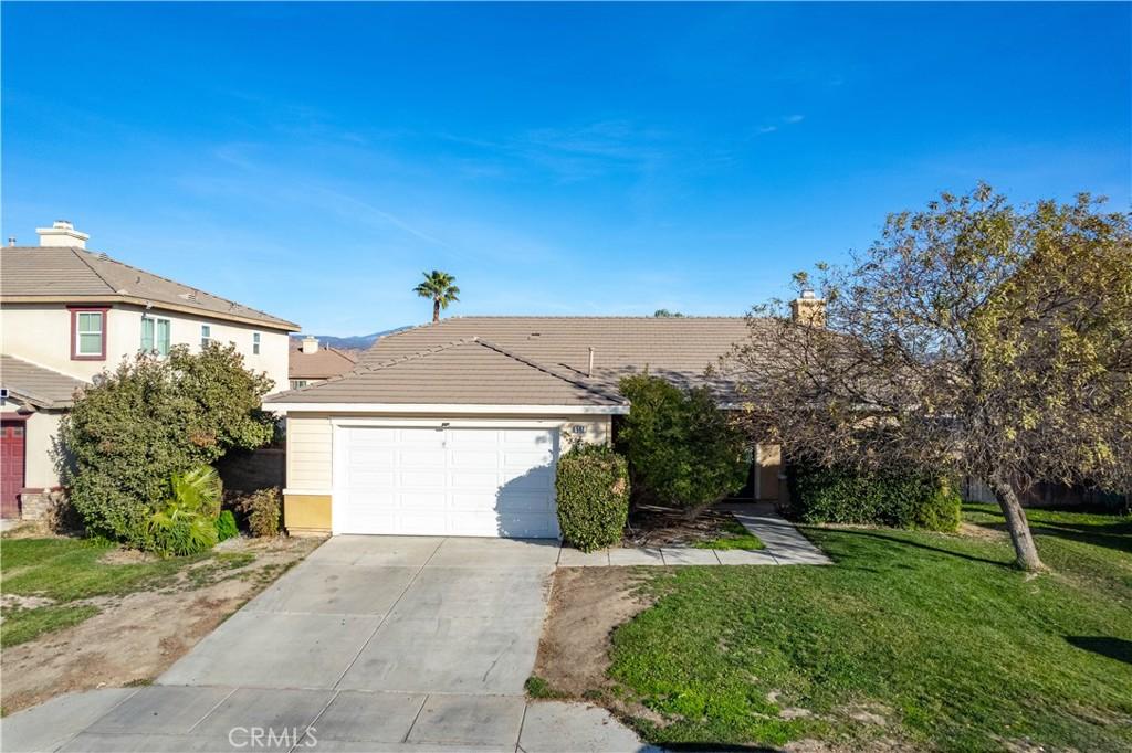 view of front of property with a tiled roof, driveway, an attached garage, and a front lawn