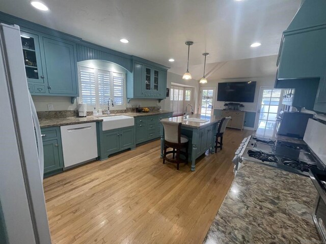 kitchen featuring sink, white dishwasher, a kitchen breakfast bar, an island with sink, and pendant lighting