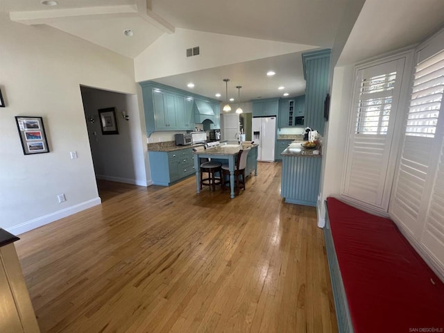 kitchen featuring premium range hood, a center island, hanging light fixtures, white fridge with ice dispenser, and light hardwood / wood-style floors