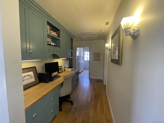 office with dark hardwood / wood-style flooring, built in desk, and washer and dryer