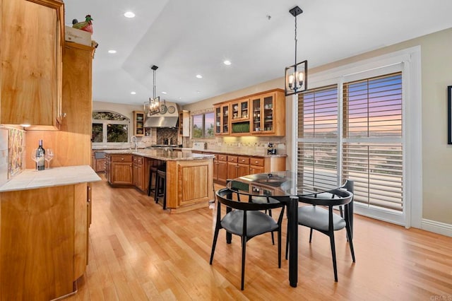 kitchen with hanging light fixtures, a healthy amount of sunlight, vaulted ceiling, and a kitchen island