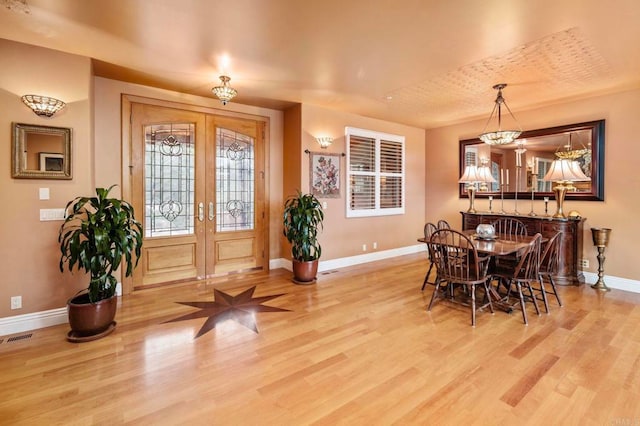 entryway with french doors, an inviting chandelier, and light hardwood / wood-style floors