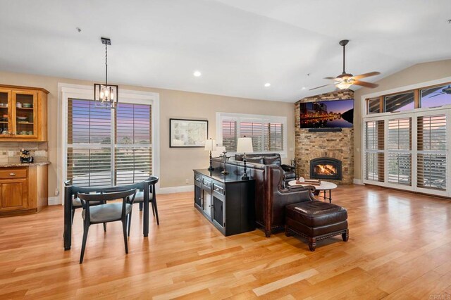 kitchen with vaulted ceiling, decorative backsplash, ceiling fan, light wood-type flooring, and a brick fireplace