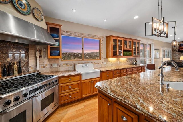 kitchen featuring double oven range, hanging light fixtures, sink, and extractor fan