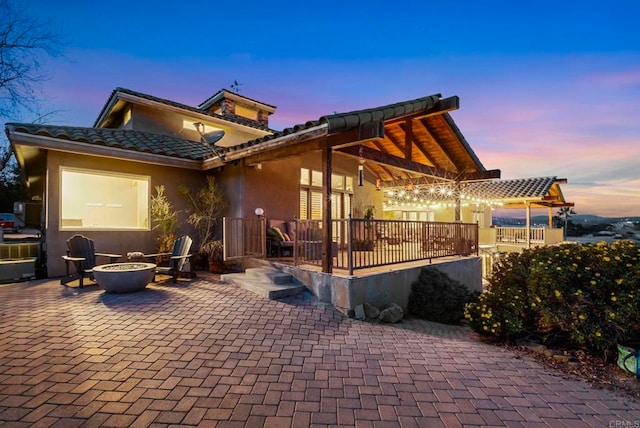 back house at dusk with an outdoor fire pit and a patio