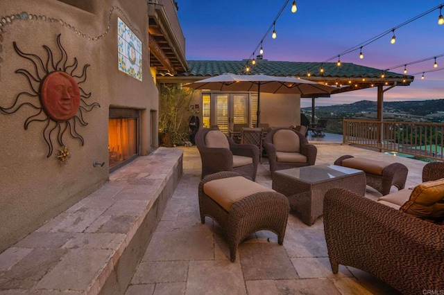 patio terrace at dusk with an outdoor living space with a fireplace