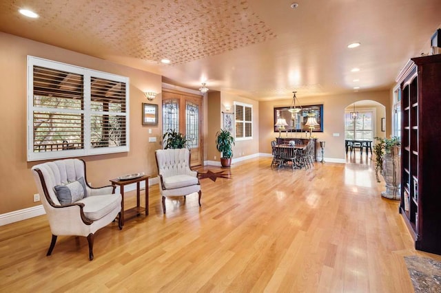 sitting room with light wood-type flooring and an inviting chandelier