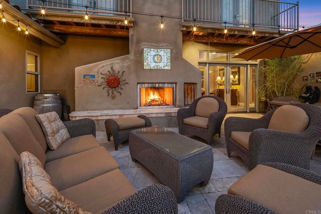 patio terrace at dusk featuring a balcony and french doors