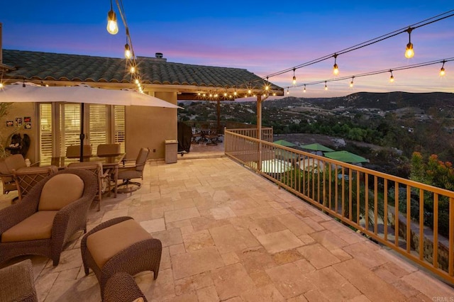 patio terrace at dusk featuring a balcony