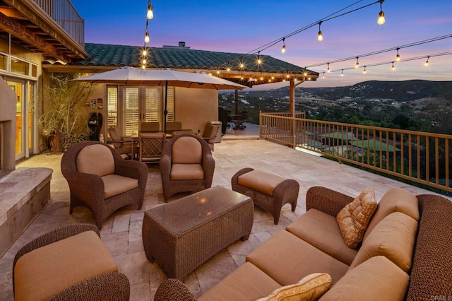 patio terrace at dusk featuring outdoor lounge area and a balcony