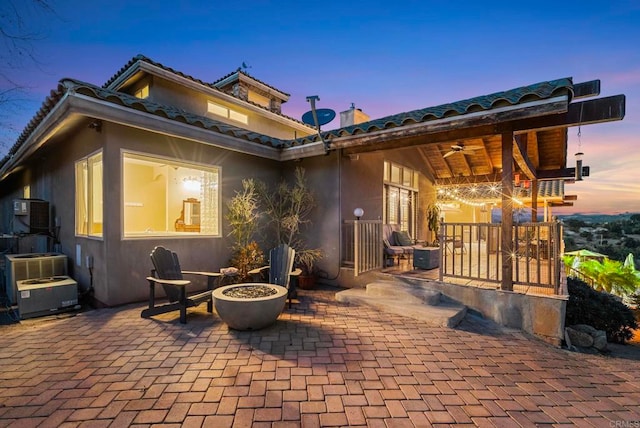 back house at dusk featuring ceiling fan, central AC, and a patio