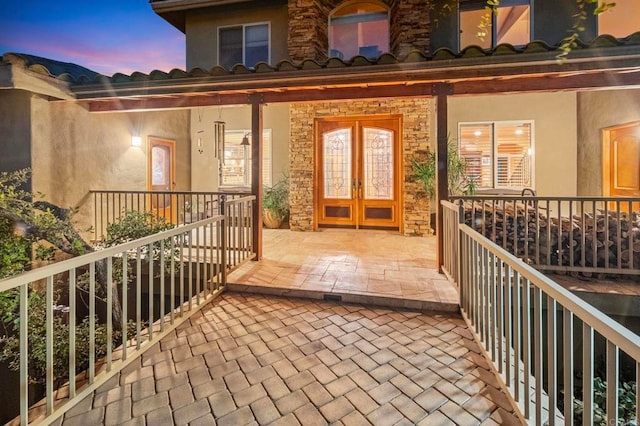 balcony at dusk with french doors and a porch