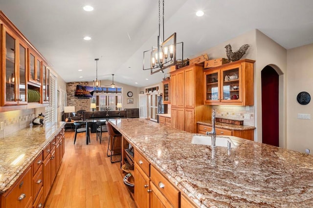 kitchen with a breakfast bar area, lofted ceiling, tasteful backsplash, and decorative light fixtures