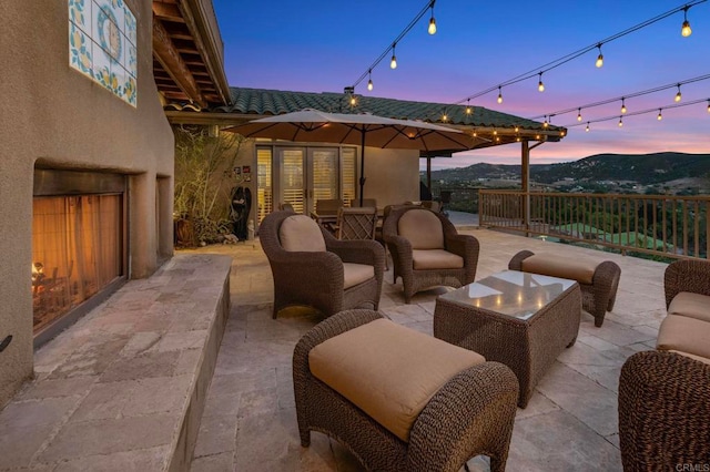 patio terrace at dusk featuring a mountain view and an outdoor living space with a fireplace