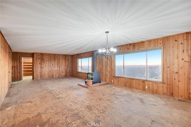 unfurnished living room with a water view, a wood stove, and a chandelier