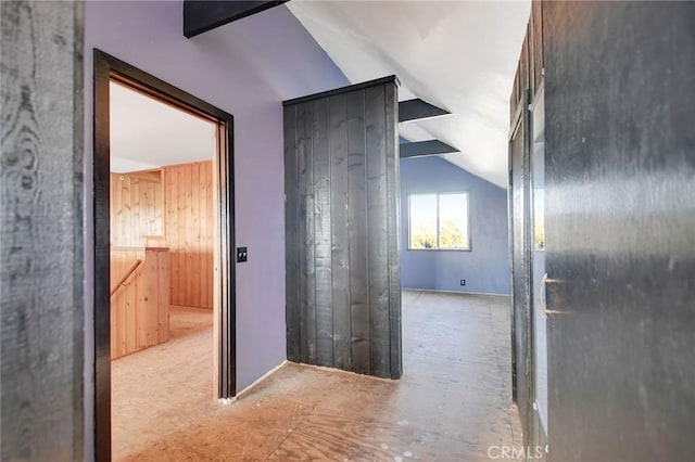 hallway with wooden walls and vaulted ceiling