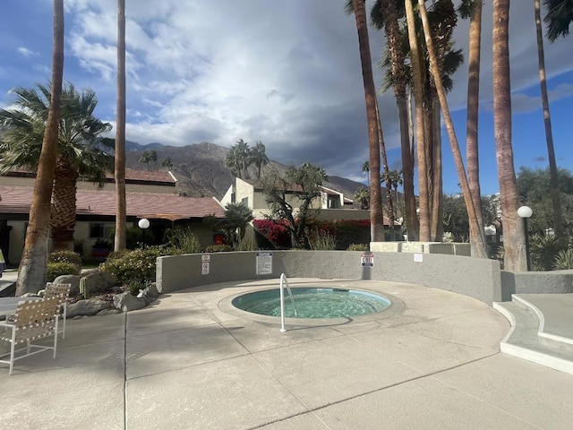 view of pool with a community hot tub, a mountain view, and a patio area