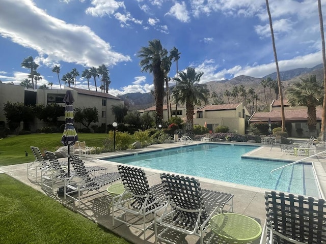 view of swimming pool with a yard, a mountain view, and a patio area