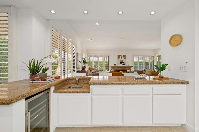 kitchen featuring light tile patterned floors, wine cooler, white cabinets, and stone countertops