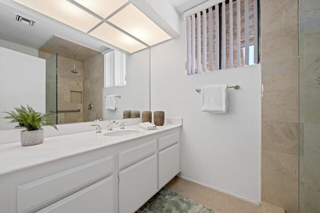 bathroom featuring vanity, a tile shower, and tile patterned flooring