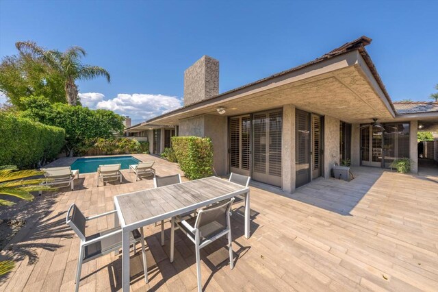 wooden terrace featuring ceiling fan and a fenced in pool