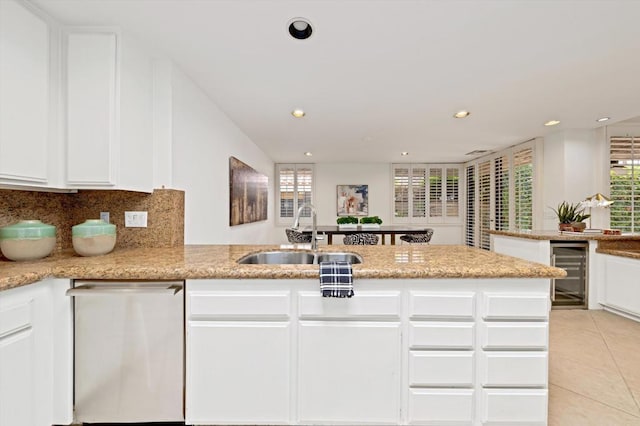 kitchen featuring kitchen peninsula, stainless steel dishwasher, beverage cooler, and sink