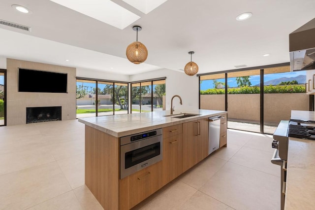 kitchen featuring range, hanging light fixtures, wall oven, light stone counters, and a large fireplace