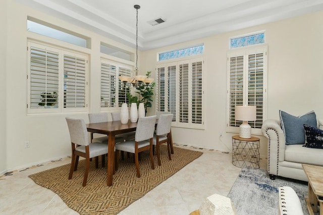 dining space featuring an inviting chandelier, a raised ceiling, and tile patterned flooring