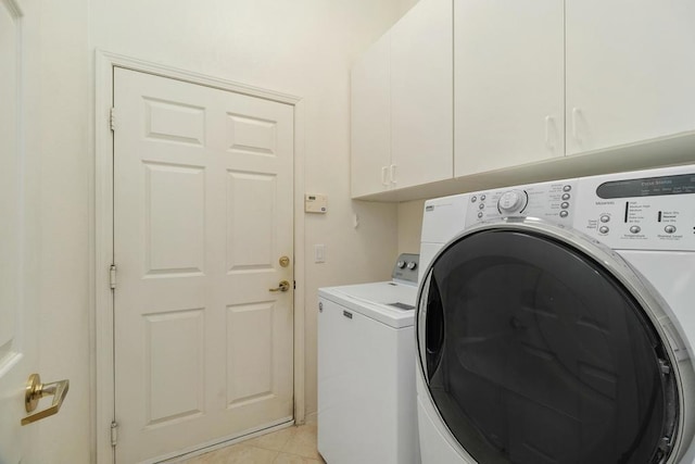 laundry room featuring cabinets, light tile patterned floors, and washing machine and clothes dryer